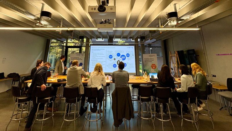 Teilnehmende des Kick-off-Meetings des Projekts BaStI sitzen in einem modernen Seminarraum und diskutieren vor einer Präsentationsfolie über das Batterie-Start-up-Ökosystem