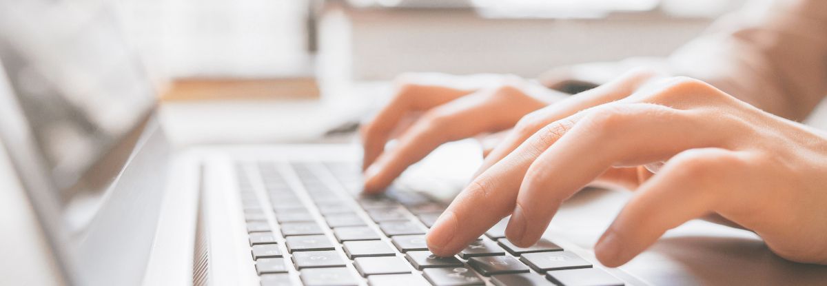 Hände tippen auf der Tastatur eines Laptops
